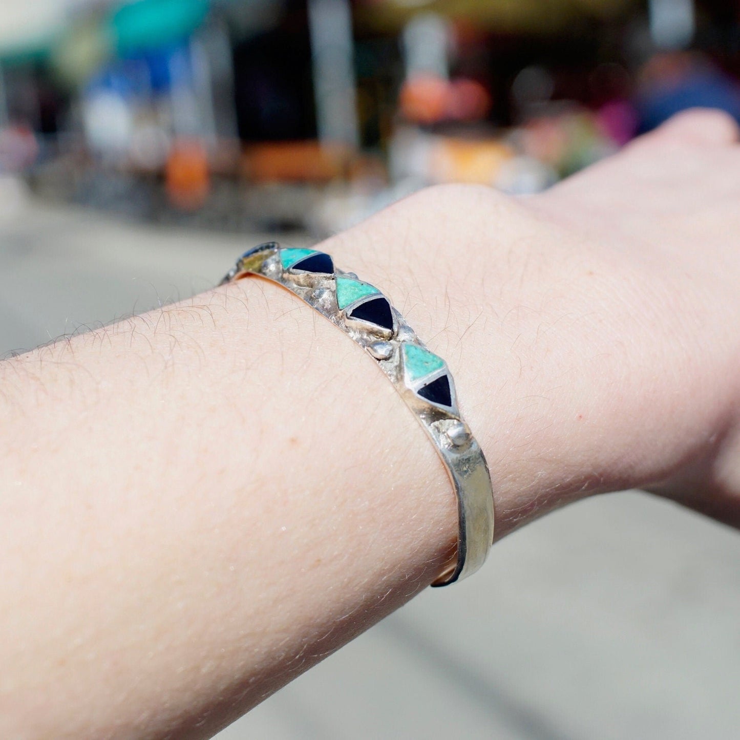 Vintage 70's Zuni inlaid turquoise and onyx silver cuff bracelet with triangle pattern on a person's wrist, showing the intricate Native American craftsmanship and petite size of the 4 3/4" long silver cuff.