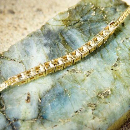 Vintage gold plated sterling silver cubic zirconia diamond bar bracelet with 2.5mm herringbone chain and 12 brilliant CZ diamonds, measuring 7 1/8 inches long, on textured stone background