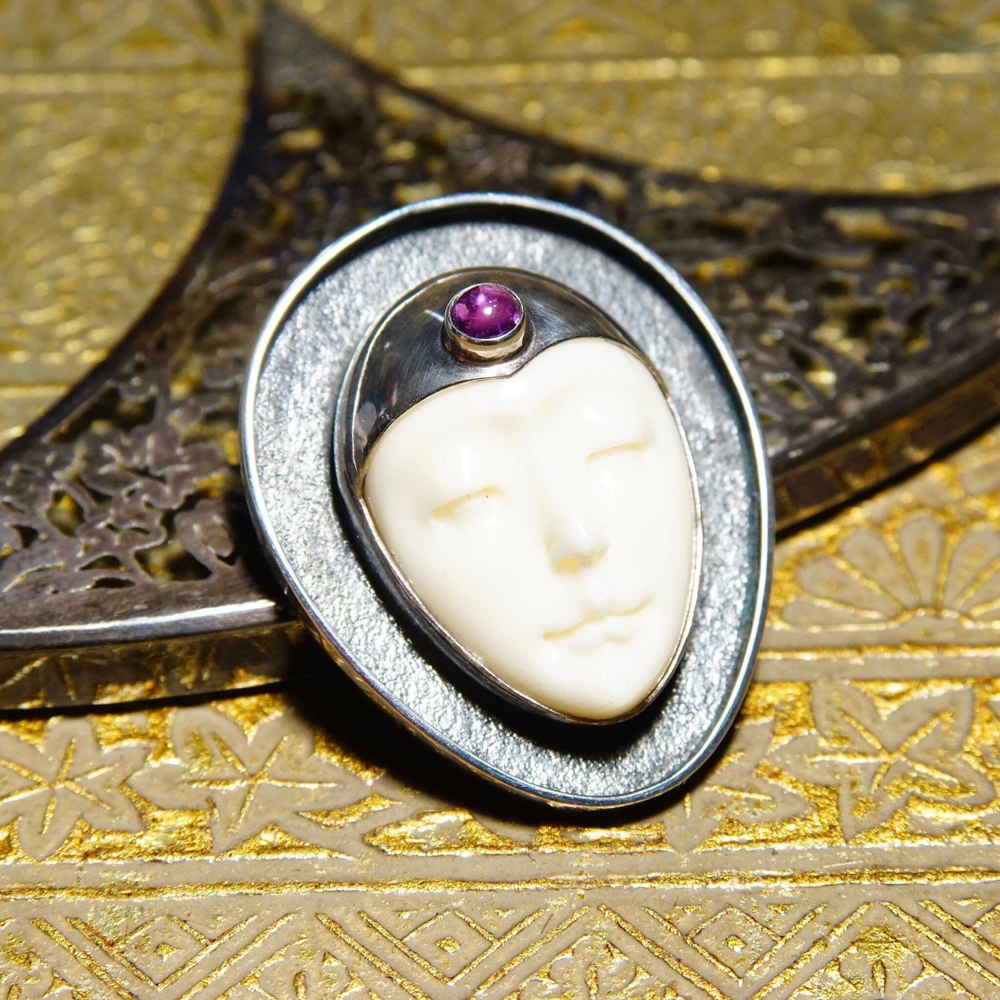 Vintage Sajen sterling silver amethyst and carved bovine bone Moon Goddess pendant brooch on golden textured background, unique extraterrestrial-inspired 925 jewelry piece measuring 1 1/2 inches.