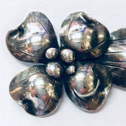 Vintage silver flower brooch with textured, hammered petals and a shiny, reflective finish, likely from John Wanamaker jewelry collection.