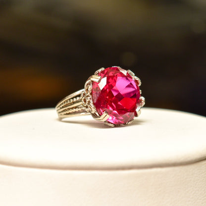10K white gold pink ruby cocktail ring with ornate filigree setting, featuring a large synthetic ruby gemstone. Art Deco style ring in a size 6 3/4 US.