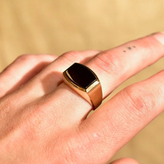 14K yellow gold black onyx signet ring with sleek modernist design, featuring satin and polished finish, shown on finger, size 8 3/4 US.