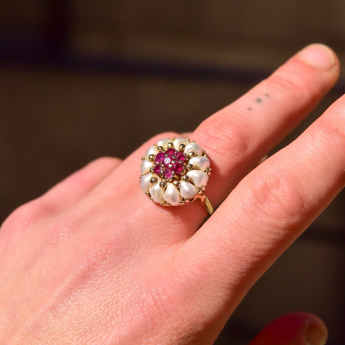 14K yellow gold ring featuring a round cluster of white pearls and pink rubies in a domed floral design, shown on a hand, estate jewelry, size 9 US.