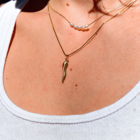 14K gold Italian horn necklace with brushed finish and delicate pearl chain, featuring a mini puffed cornicello good luck charm pendant.