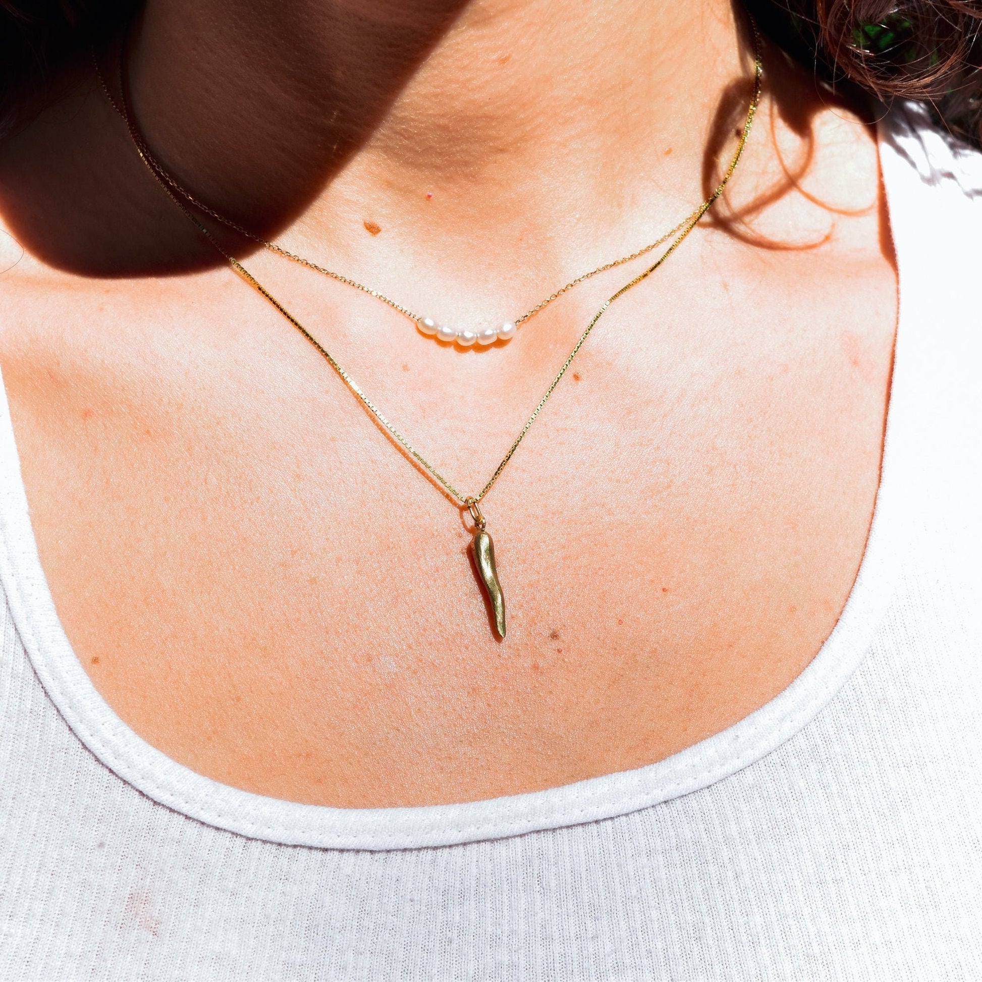 14K gold Italian horn necklace worn on woman's neck, mini brushed yellow gold cornicello pendant charm, vintage good luck amulet jewelry