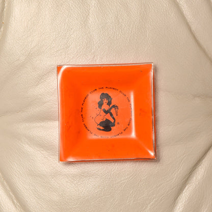 Orange glass vintage Playboy Club ashtray featuring Leroy Neiman Femlin illustration from the 1960s, small 4.75 inch square trinket dish.