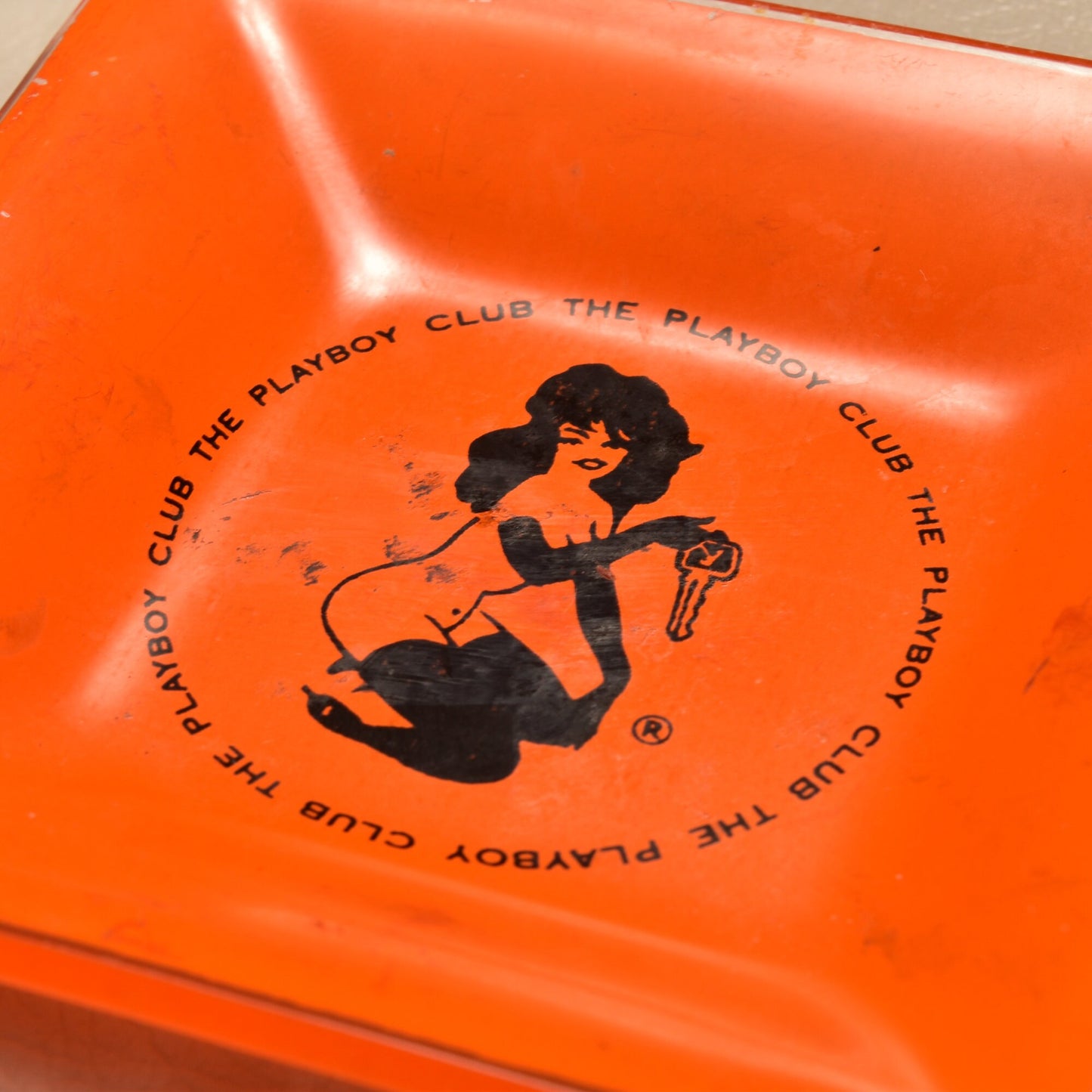 Vintage orange glass Playboy Club ashtray featuring Leroy Neiman's Femlin illustration from the 1960s, measuring 4.75 inches and suitable as a small trinket dish.