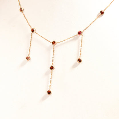 14K gold choker necklace with garnet bezel-set stations and three dangling chain tassels, delicate minimalist design, 16 inch length chain.