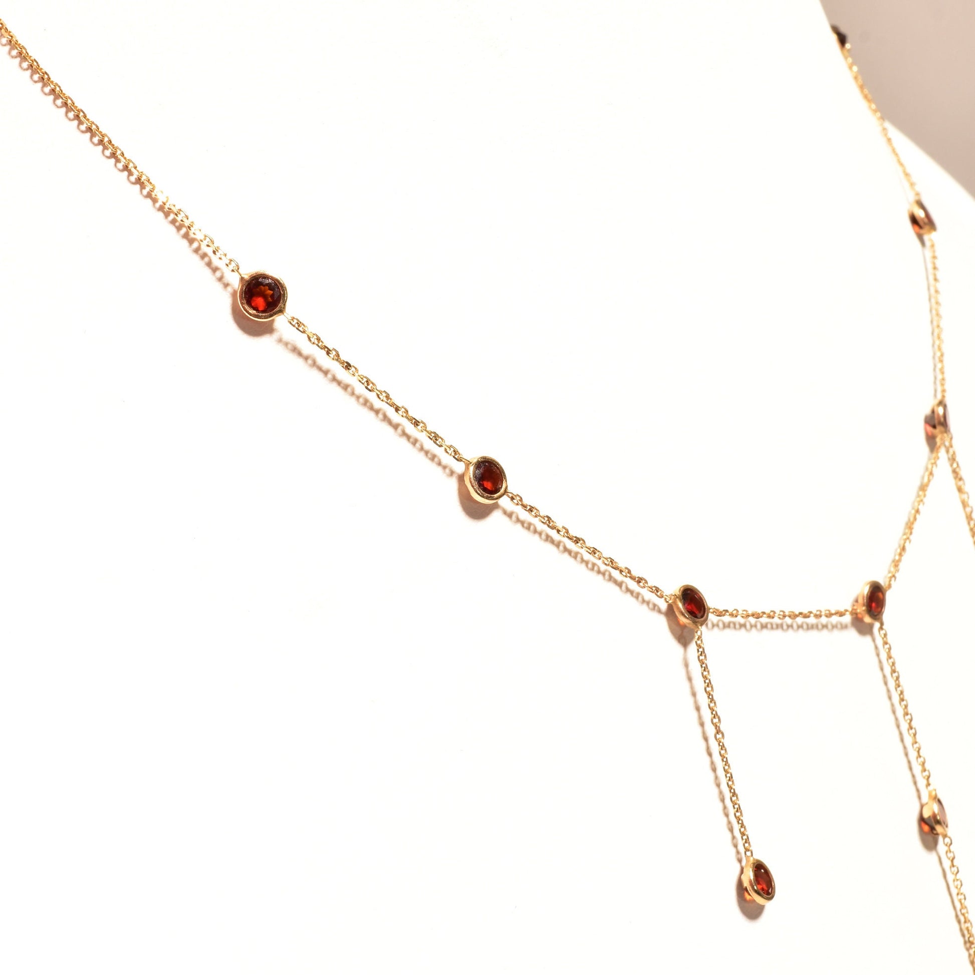 Elegant 14K gold chain necklace with garnet bezel-set stations and three dainty drop tassels, minimalist choker style, 16 inches long.