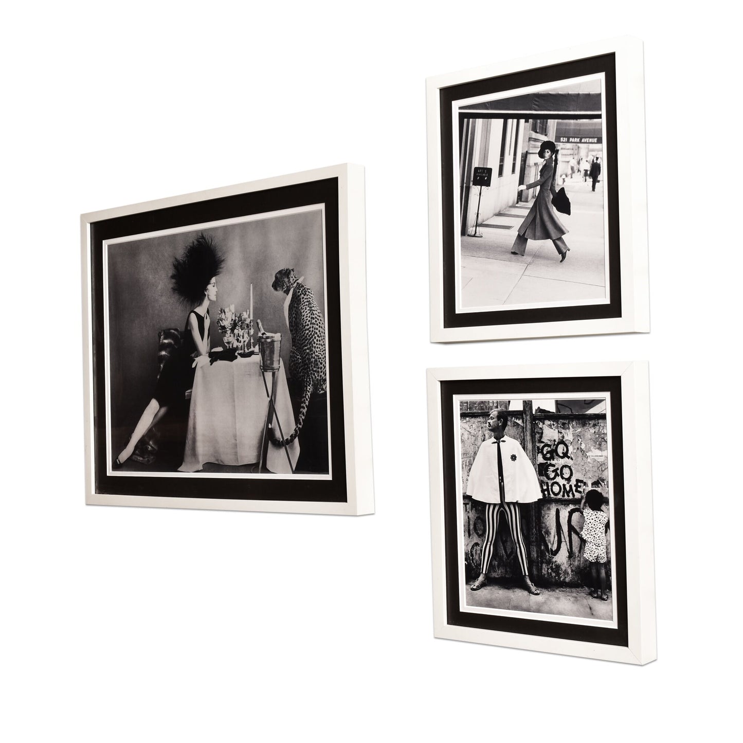 Three black and white fashion photographs from vintage Vogue magazines in black frames hung on a white wall, depicting stylish women in dresses and coats from past decades