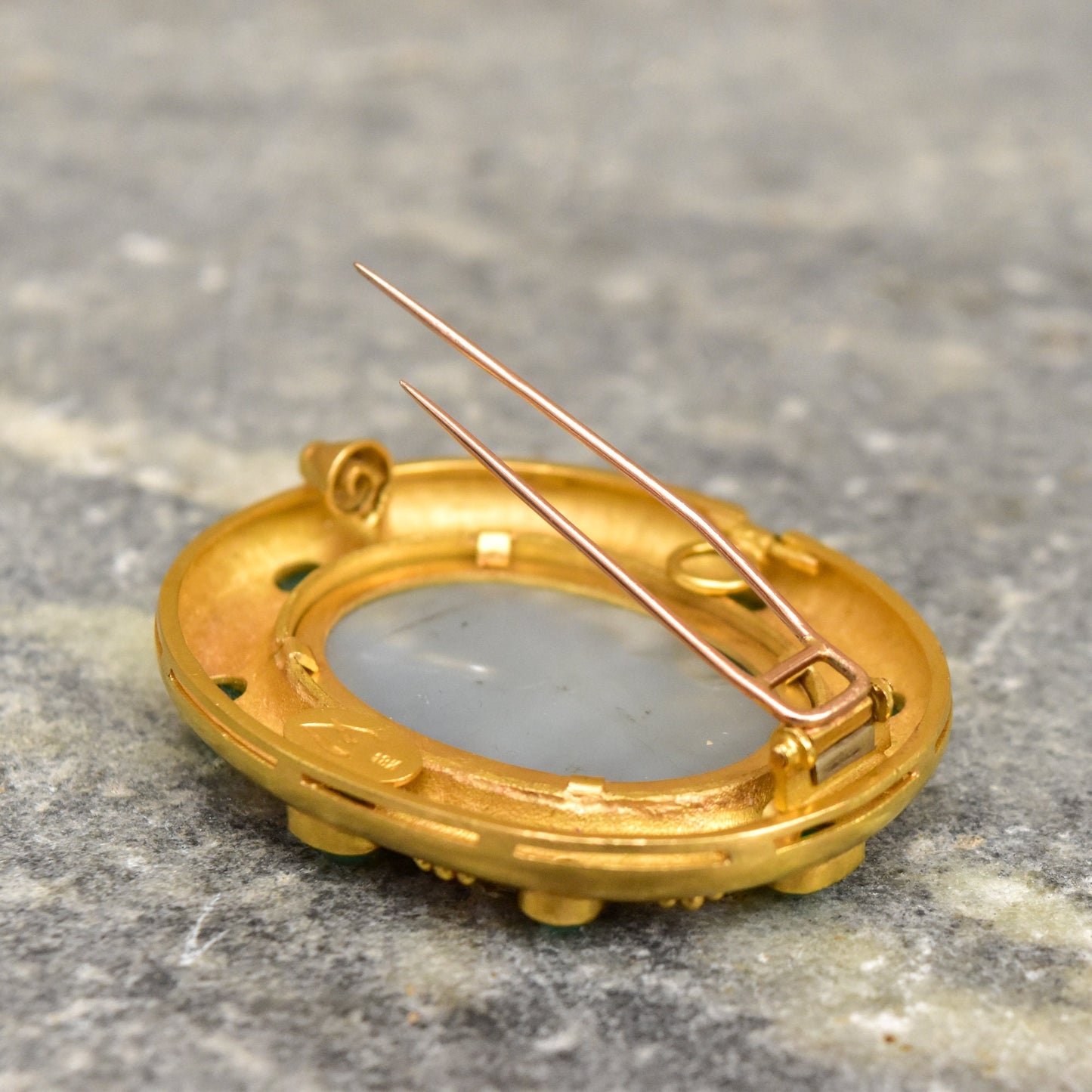 18K gold brooch pendant with oval Venetian glass intaglio, three gold prongs securing the glass, and mother of pearl backing, displayed on gray textured surface.