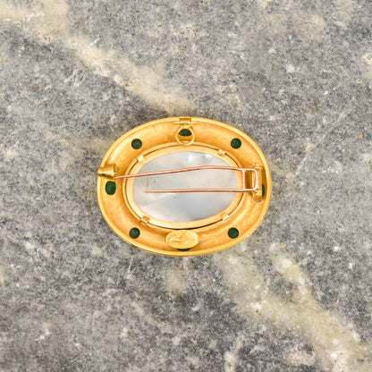 18K gold brooch with oval Venetian glass intaglio, 4 green cabochons, and mother of pearl backing on a grey marble background
