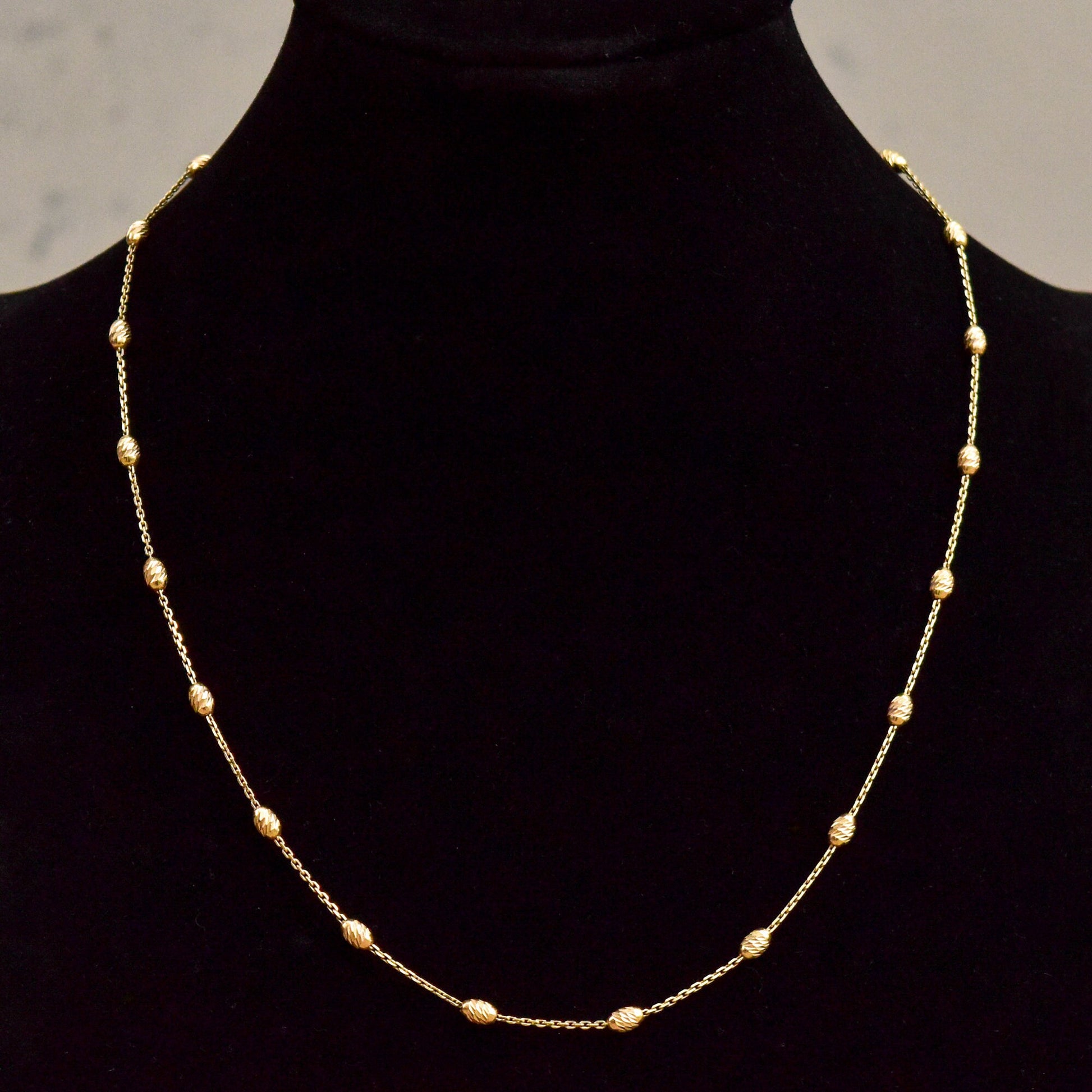 Italian vermeil sterling silver beaded station necklace with engraved honey dipper beads on a 1mm cable link chain, 17 3/4 inches long, displayed on a black velvet jewelry bust.