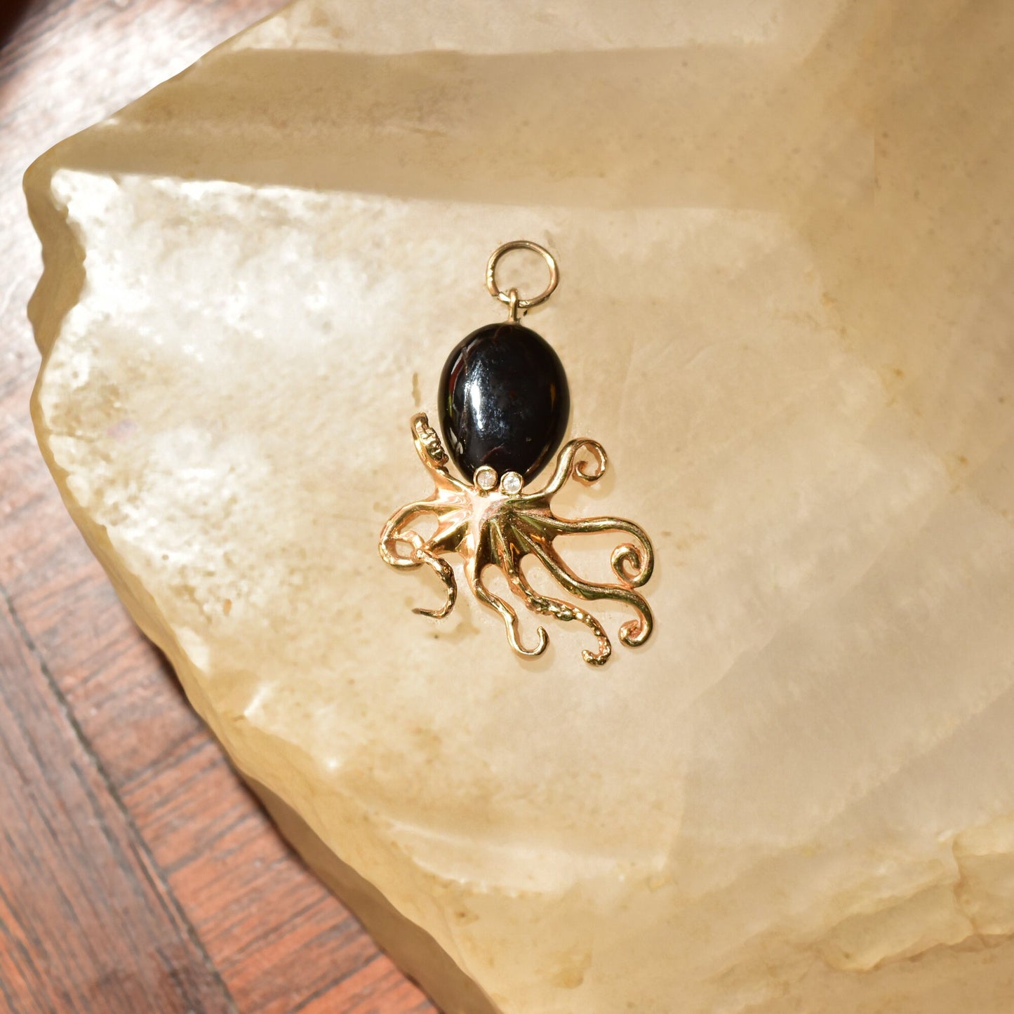 10K yellow gold octopus pendant with black coral cabochon and diamond accent, aquatic-themed 3D jewelry pendant measuring 38mm in length on crystal quartz slab
