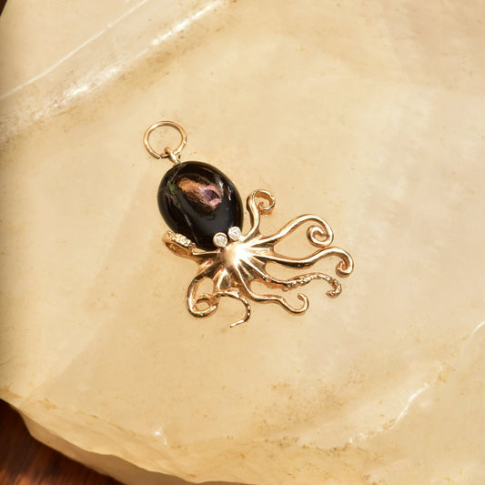 10K yellow gold octopus pendant with black coral and diamond eye, aquatic-themed 3D jewelry measuring 38mm in size on textured beige background