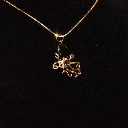 10K yellow gold octopus pendant necklace with black coral and diamond accents on a thin gold chain, showcased against a black background.