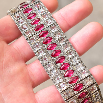 French Art Deco sterling silver articulated link bracelet with ruby paste stones, measuring 6 3/4 inches long. Estate jewelry piece featuring a wide cuff design with geometric ruby colored glass or paste accents set in an intricate silver link pattern.