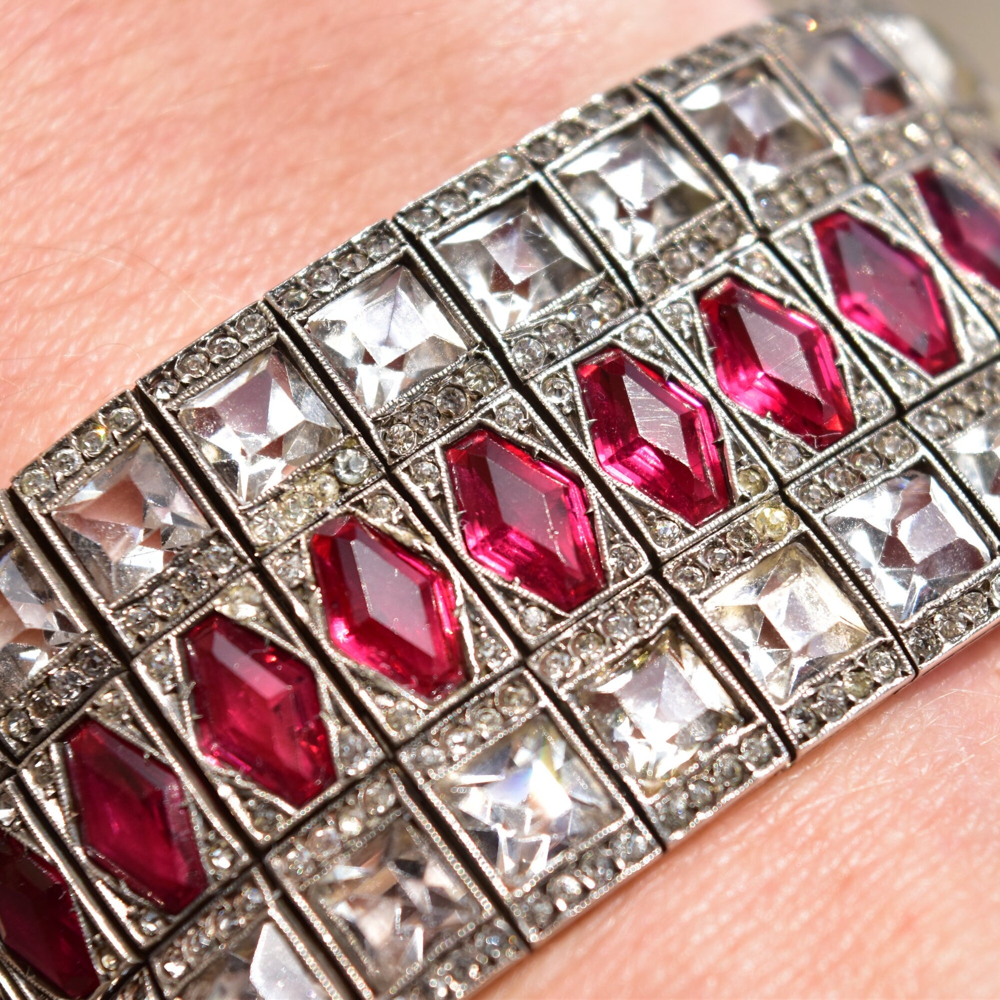 French Art Deco sterling silver bracelet with ruby paste stones in a wide articulated link cuff design, measuring 6 3/4 inches long, estate jewelry piece.