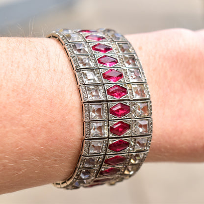 Art Deco sterling silver bracelet with articulated links featuring faceted ruby red paste stones, an elegant vintage estate jewelry cuff measuring 6 3/4 inches long, shown on a wrist.