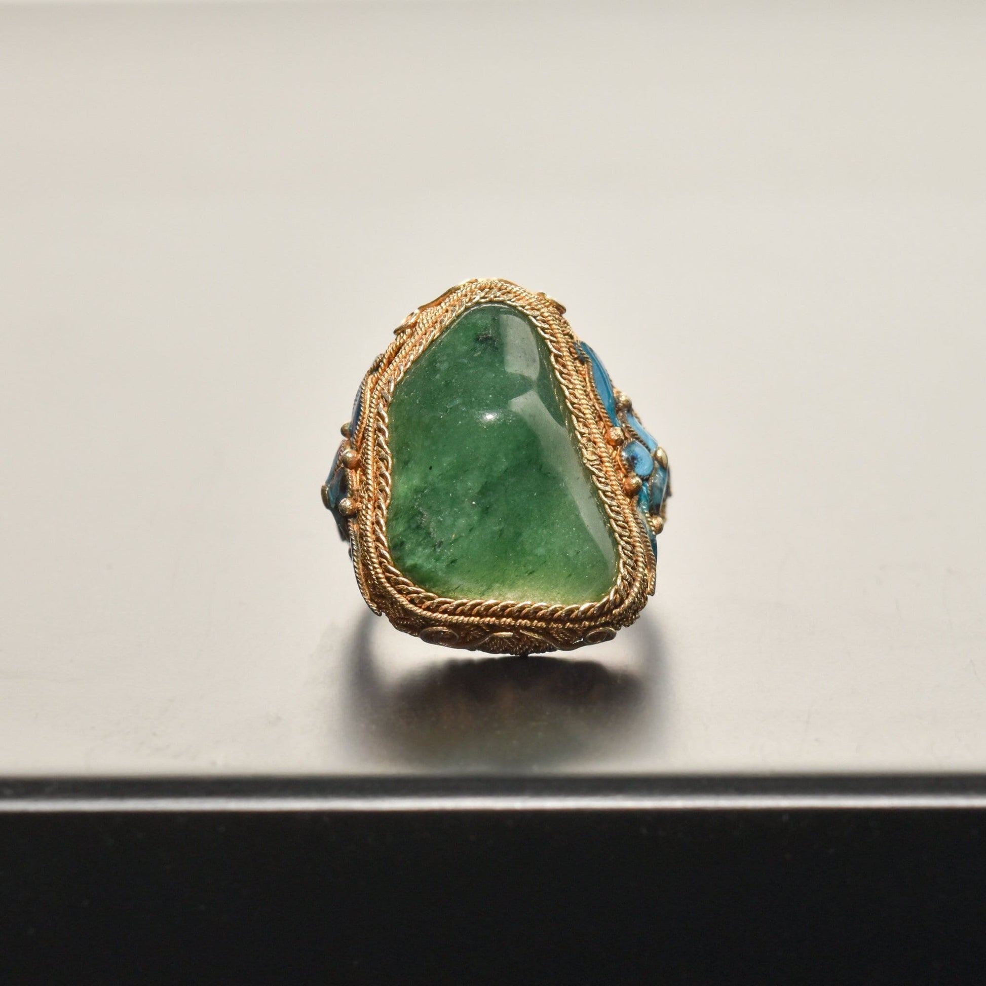 Antique Chinese export silver gilt ring featuring a polished green jade stone, intricate floral engravings, and an adjustable band to fit ring sizes 7 to 11 US.