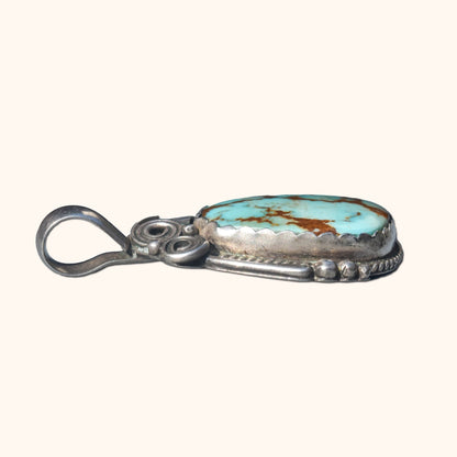 Signed Native American turquoise and sterling silver pendant with leaf swirl motifs, Navajo jewelry craftsmanship, measures 1.75 inches long.