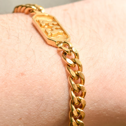 Gold tone Trifari bracelet with Gemini zodiac sign charm on a wrist, featuring a 5mm curb link chain, exemplifying astrology-themed jewelry at 7 inches long.