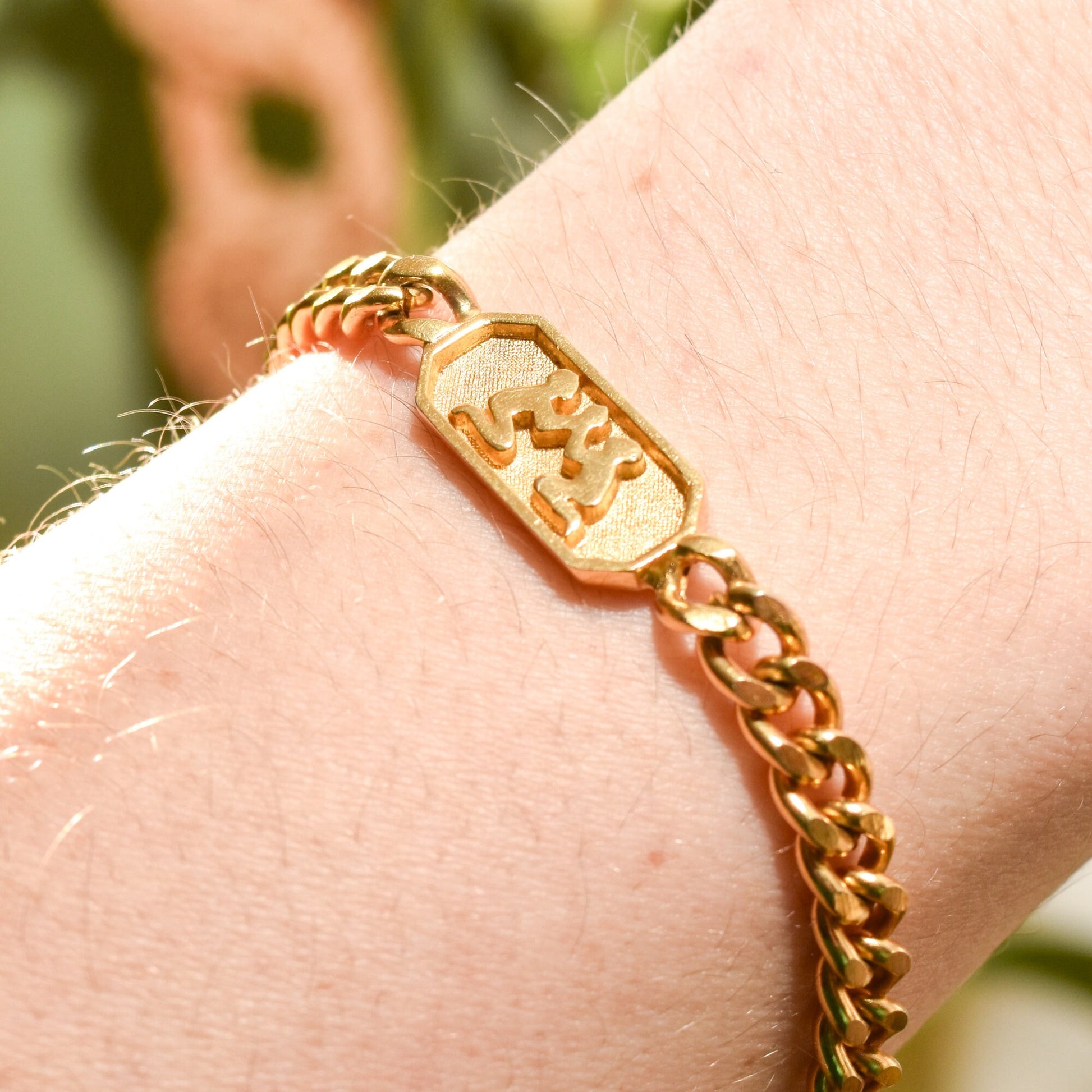 Gold-tone Vintage Trifari Gemini zodiac sign bracelet with 5mm curb link chain on a wrist, highlighting astrology-themed jewelry at 7 inches long.