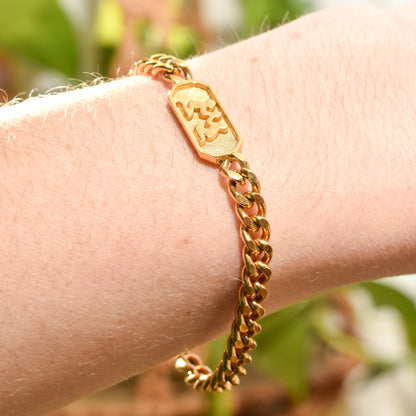 Gold tone Vintage Trifari bracelet with Gemini zodiac sign on a wrist, featuring a 5mm curb link chain, astrology-themed jewelry, 7 inches long.