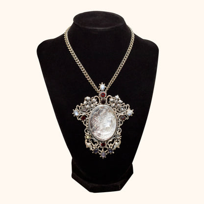 Victorian style cameo pendant brooch in sterling silver featuring a large ornate design with multiple gemstones, measuring 4 inches in length, displayed on a black mannequin bust with gold chain.