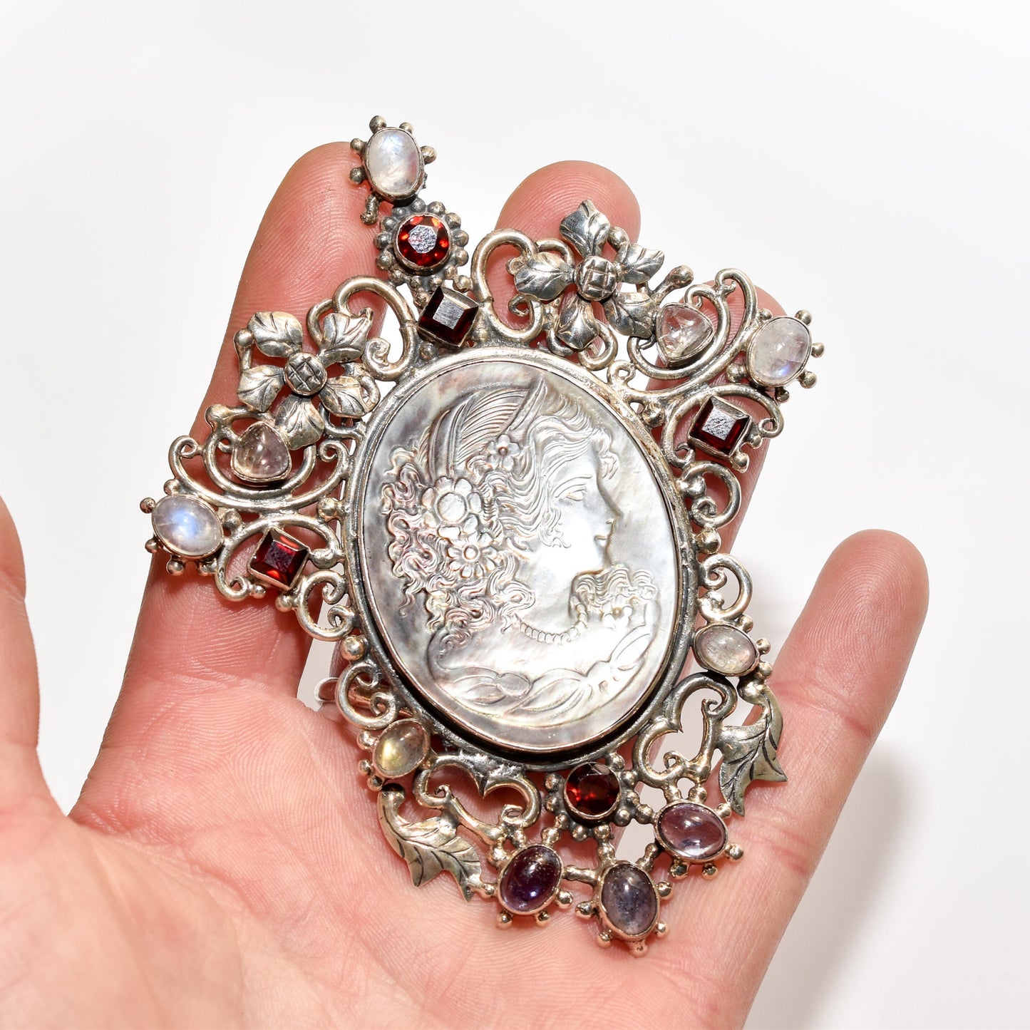 Victorian-style sterling silver cameo pendant brooch with multiple stones and ornate design, held in a hand, showing the size at 4 inches long.