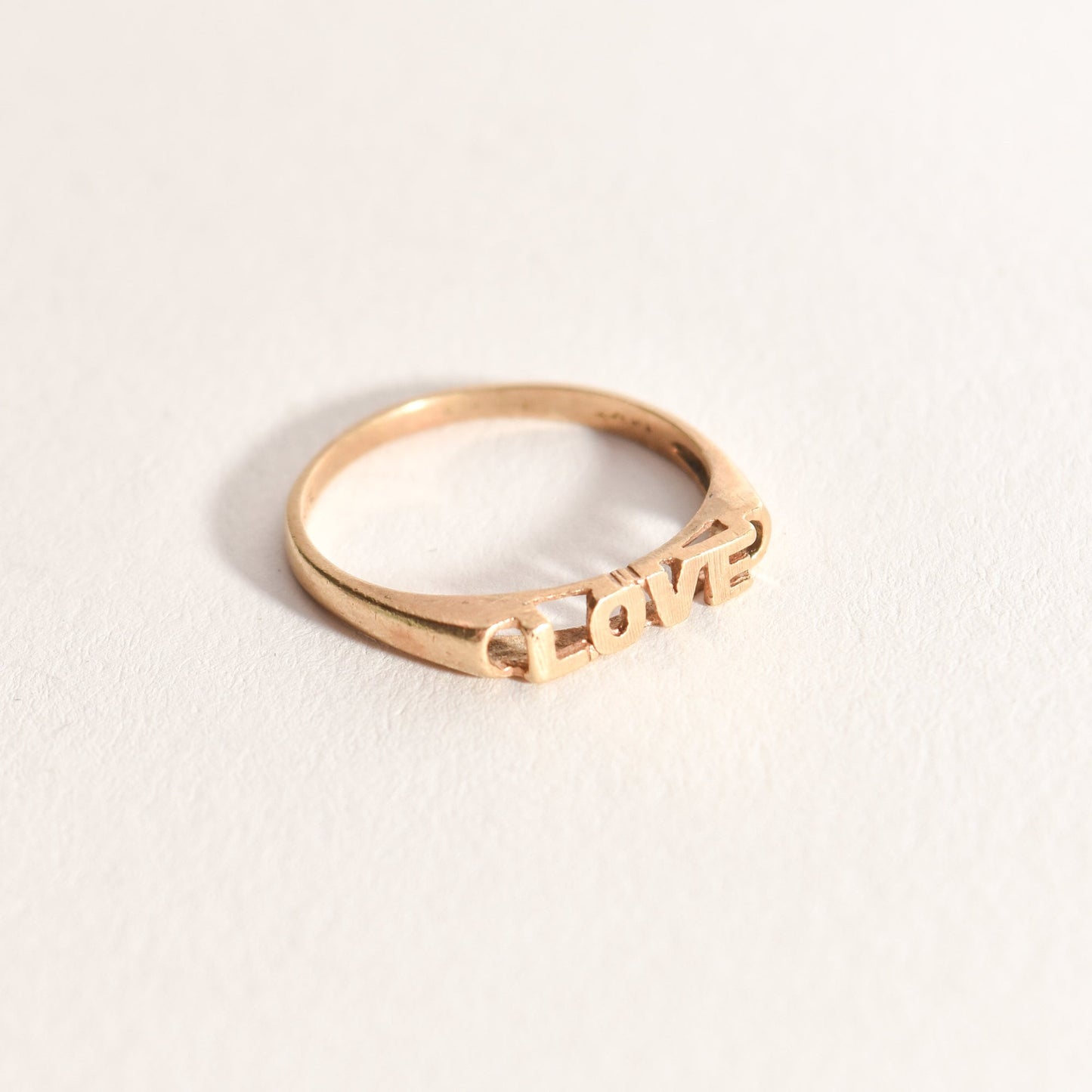 Minimalist 14K yellow gold 'LOVE' ring on a white background, cute gold stacking ring for Valentine's Day gift, size 6 3/4 US.