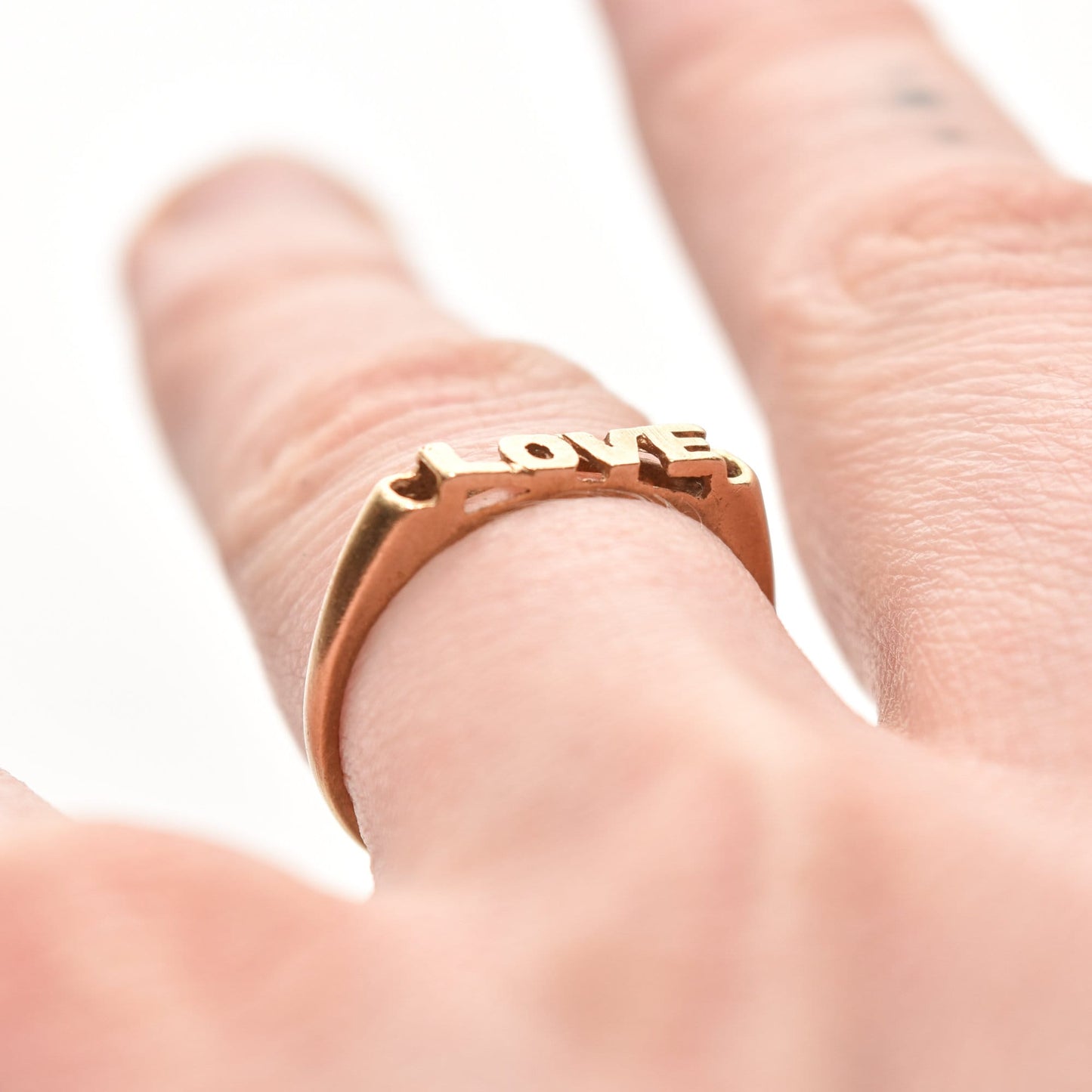 Minimalist 14K yellow gold 'LOVE' ring on finger, cute gold stacking ring for Valentine's Day gift, size 6.75 US