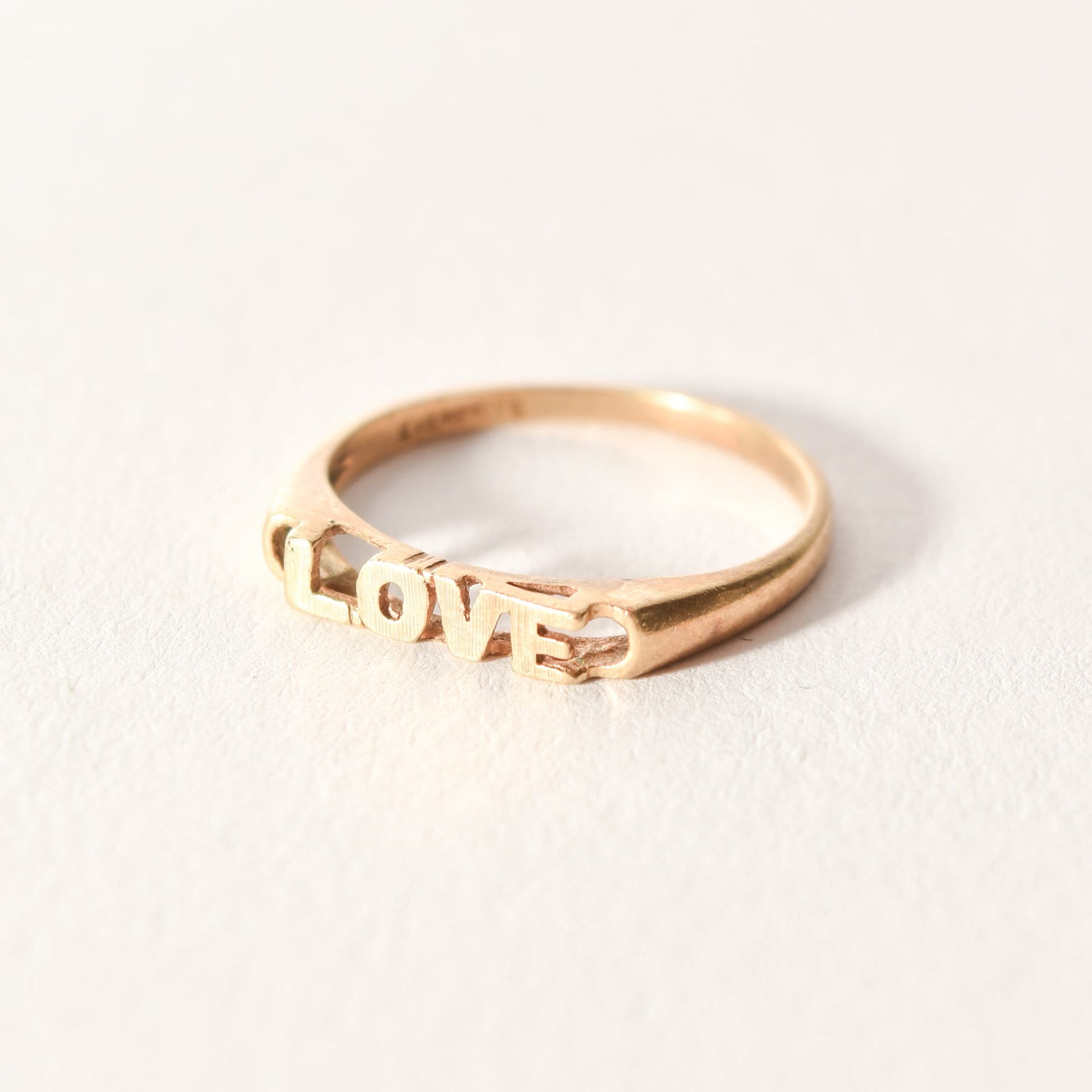Minimalist 14K yellow gold 'LOVE' ring displayed on a white background, cute gold stacking ring, perfect Valentines Day gift, size 6 3/4 US.