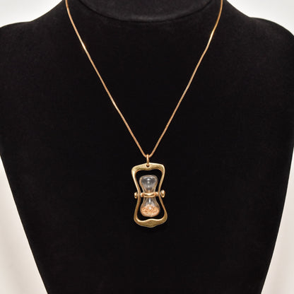 14K gold hourglass pendant with gold dust on a chain, movable swivel feature, displayed on a black mannequin, 36mm estate jewelry piece