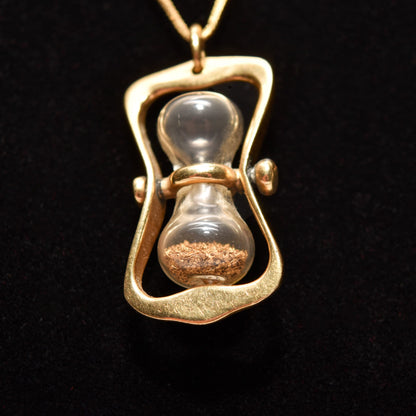 14K gold hourglass pendant with movable swivel and gold dust inside on black background, 36mm estate jewelry