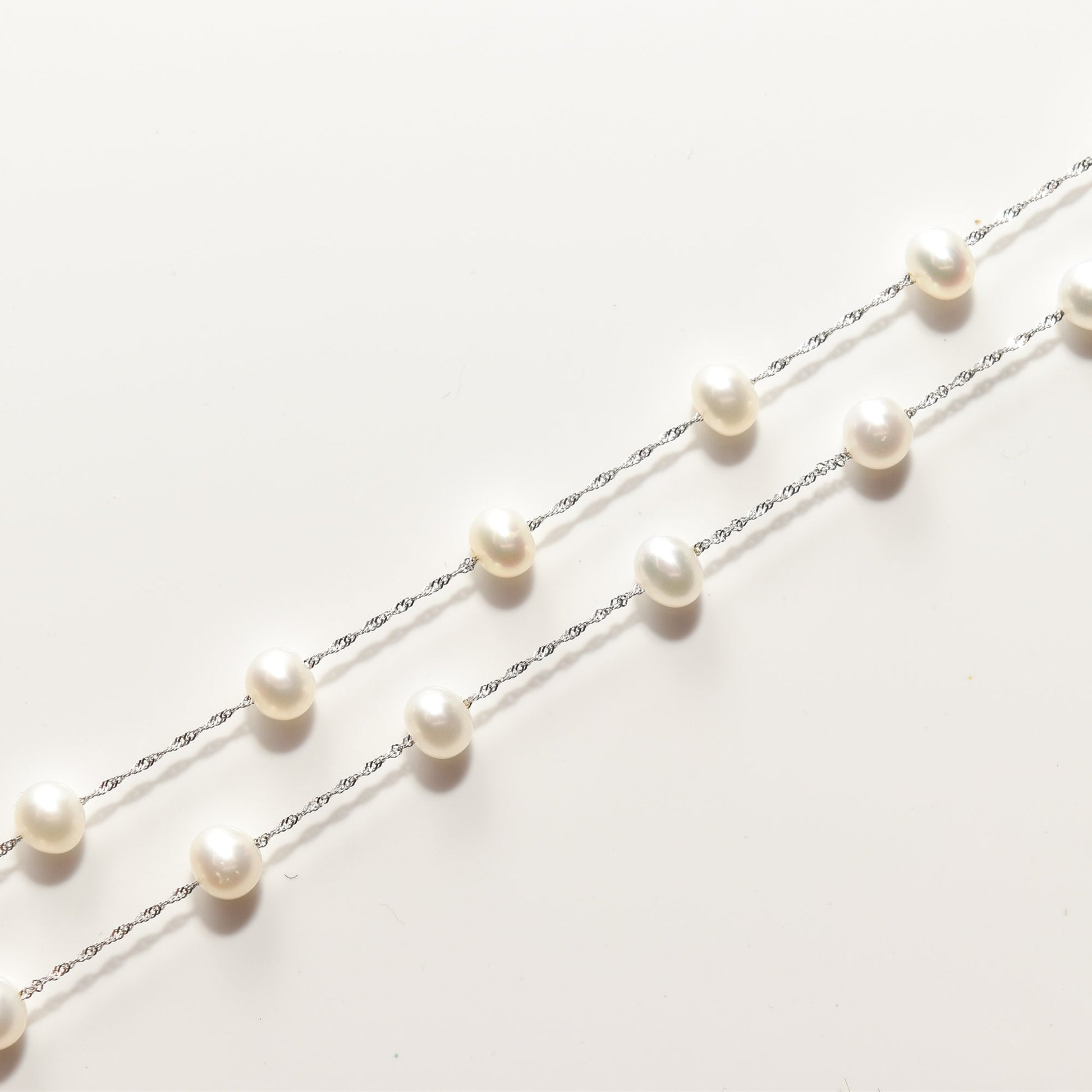 Elegant white pearl choker necklace in 14K white gold with pearls evenly spaced along a 17.75 inch chain on a white background.
