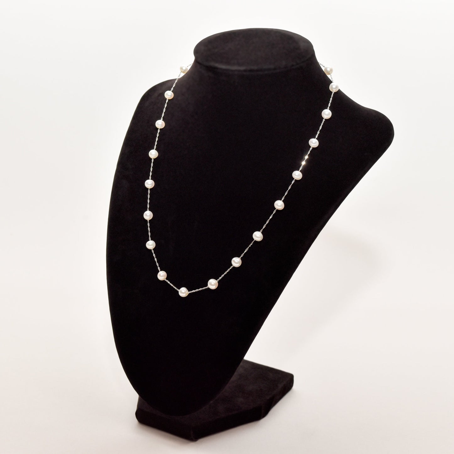 Elegant 14K white gold pearl station choker necklace displayed on a black velvet stand against a white background.