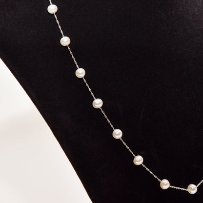 Elegant white pearl choker necklace displayed on a black background, featuring pearls in station setting on a 14K white gold chain, 17.75 inches in length.