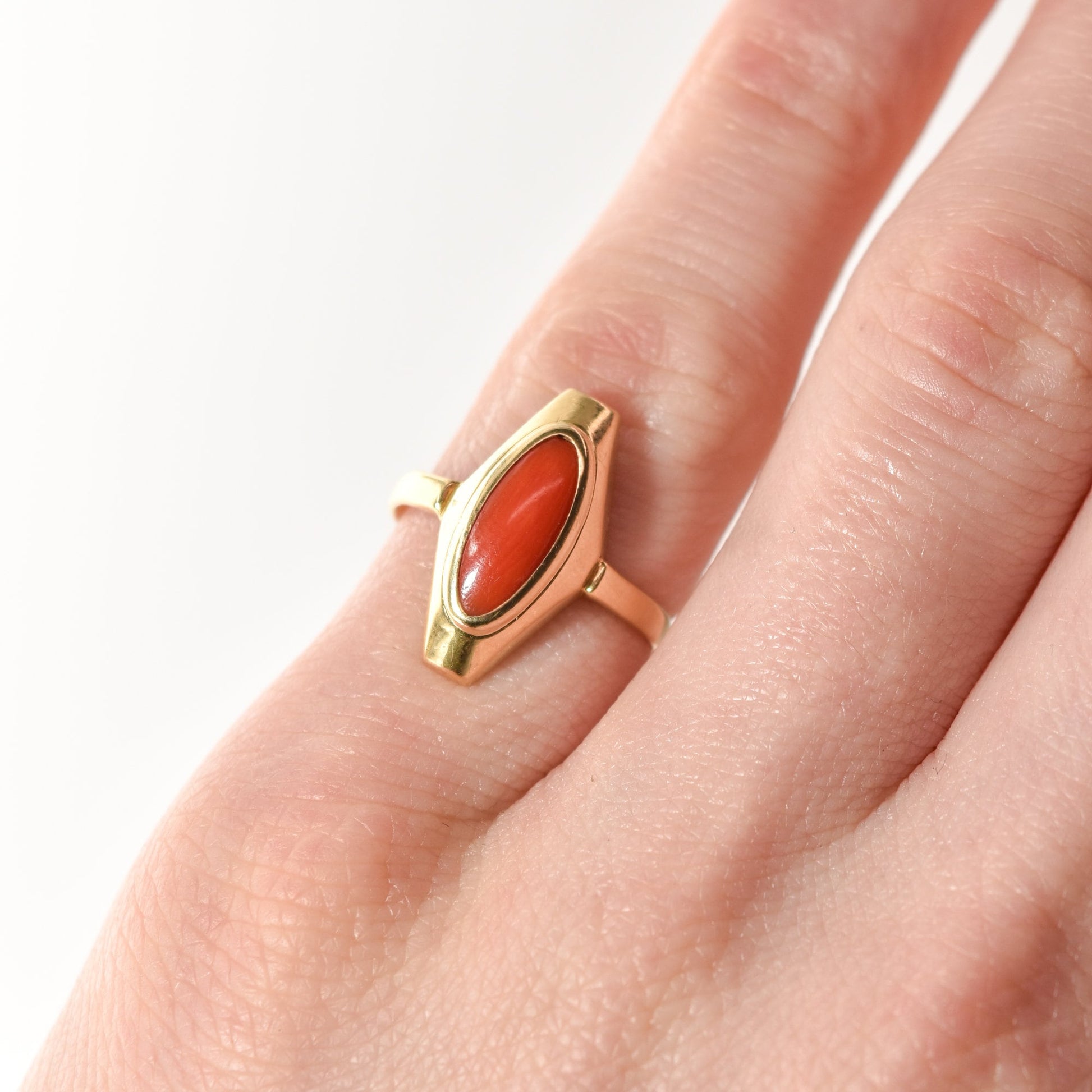Estate 18K yellow gold marquise ring with red coral on a person's finger, size 5.25 US.