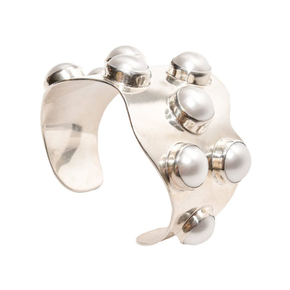 Silver TAXCO modernist sterling silver mabe pearl cuff bracelet with a wide wavy design, statement jewelry piece, size 5.75 inches, isolated on white background.