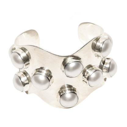 Alt text: "TAXCO modernist sterling silver mabe pearl cuff bracelet with a wide wavy design and statement style measuring 5.75 inches isolated on a white background
