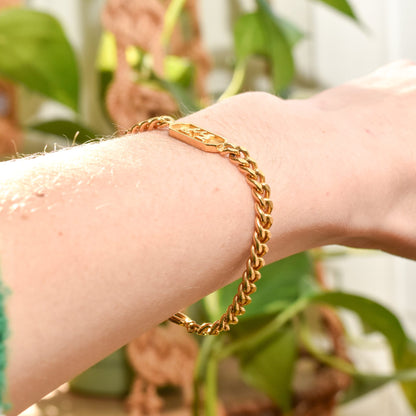 Vintage Trifari Gemini zodiac sign gold-tone bracelet on wrist, featuring 5mm curb link chain, astrology-themed jewelry, 7 inches long.