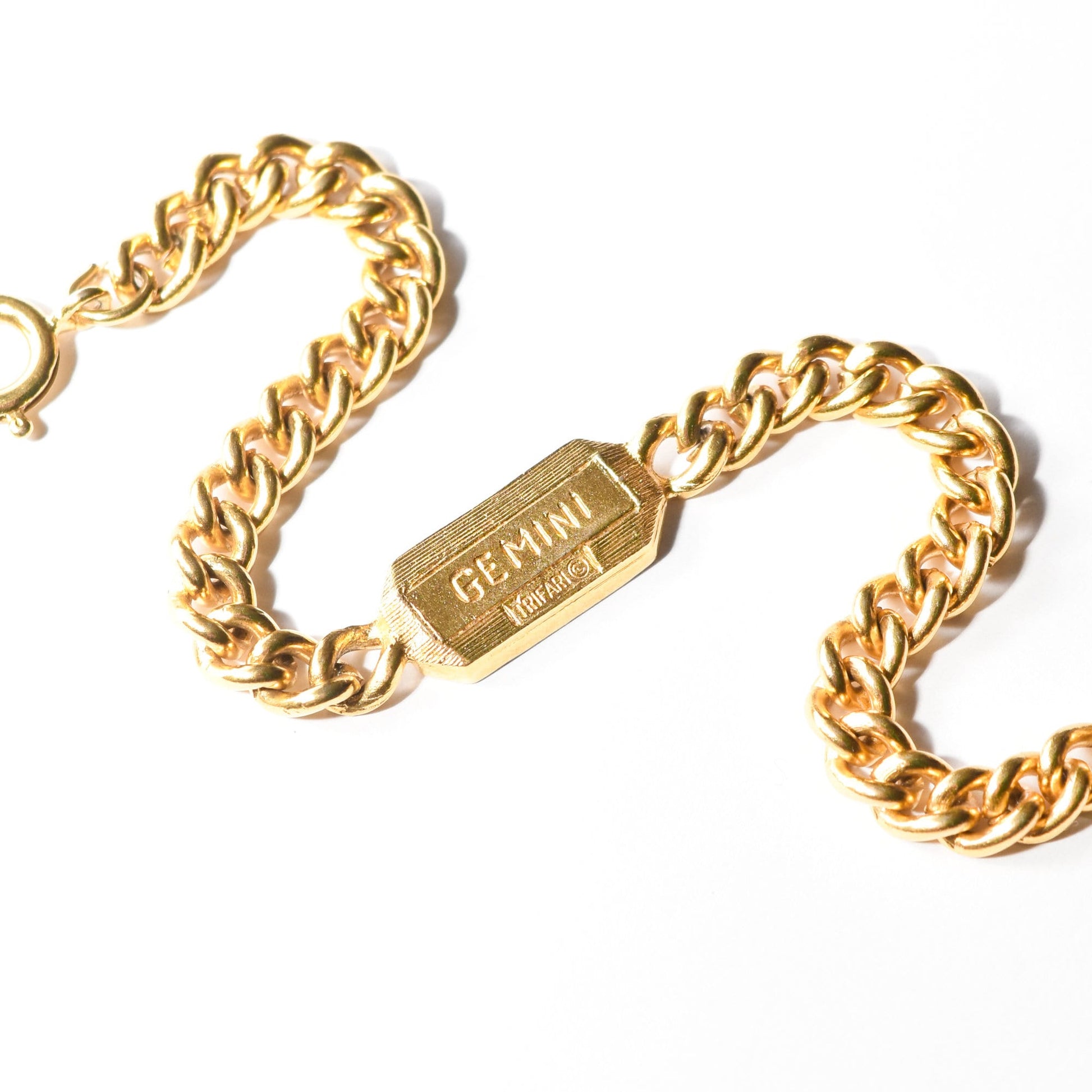 Vintage Trifari Gemini zodiac sign bracelet with gold-tone curb link chain on a white background.