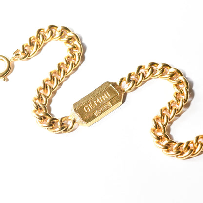 Vintage Trifari Gemini zodiac sign bracelet with gold-tone curb link chain on a white background.
