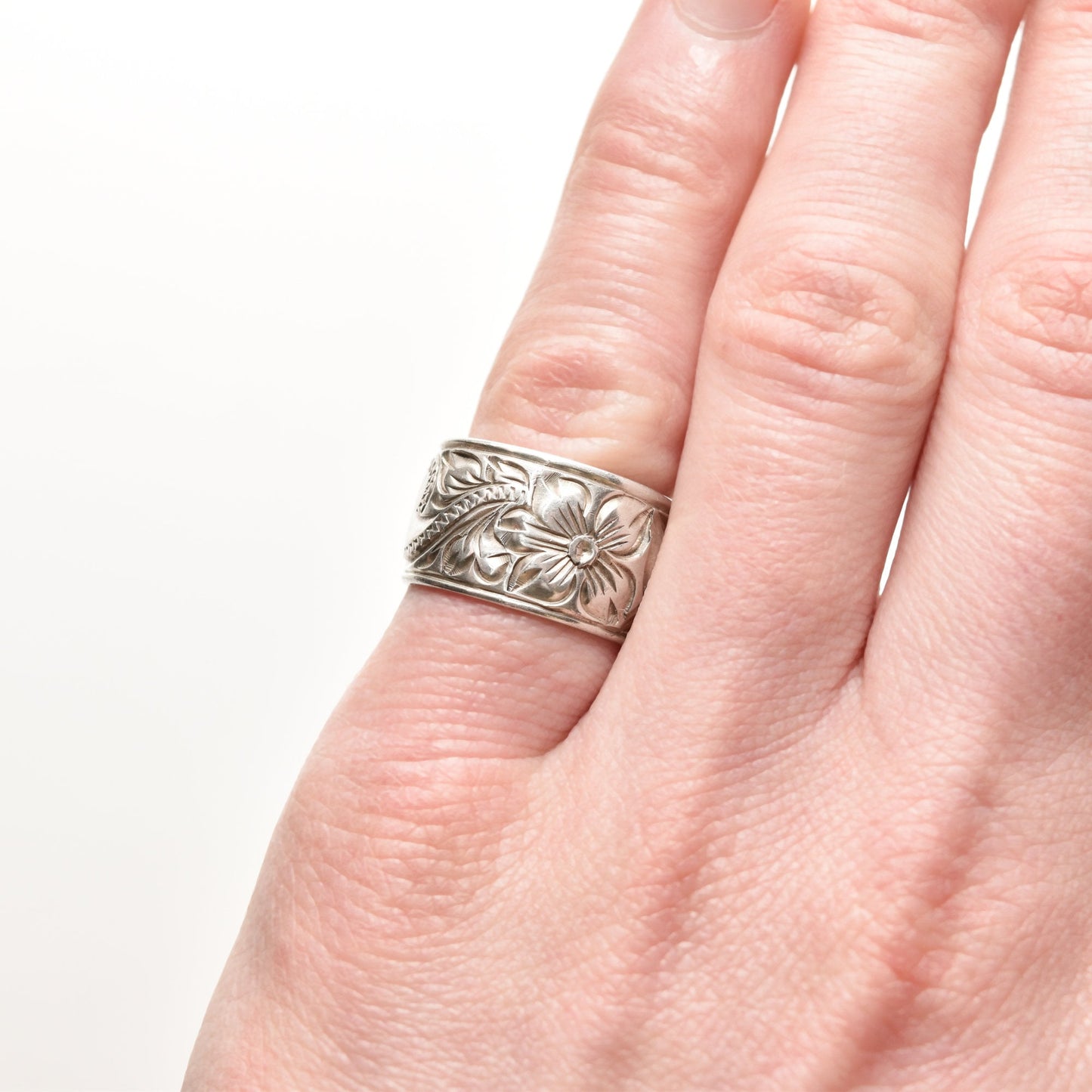Floral engraved sterling silver band ring, 11.5mm wide, in an Art Nouveau style, size 6 US, shown on a finger against a white background.