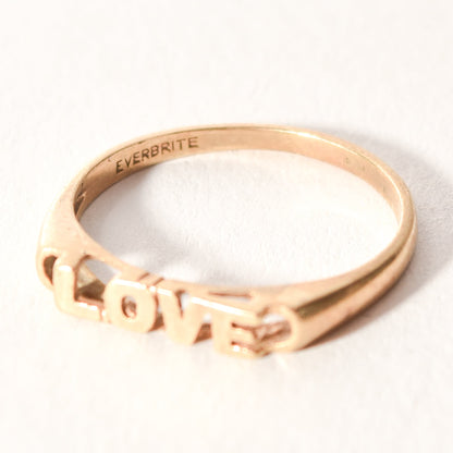 Minimalist 14K yellow gold 'LOVE' ring, cute gold stacking ring perfect for Valentine's Day gift, size 6.75 US on a white background.