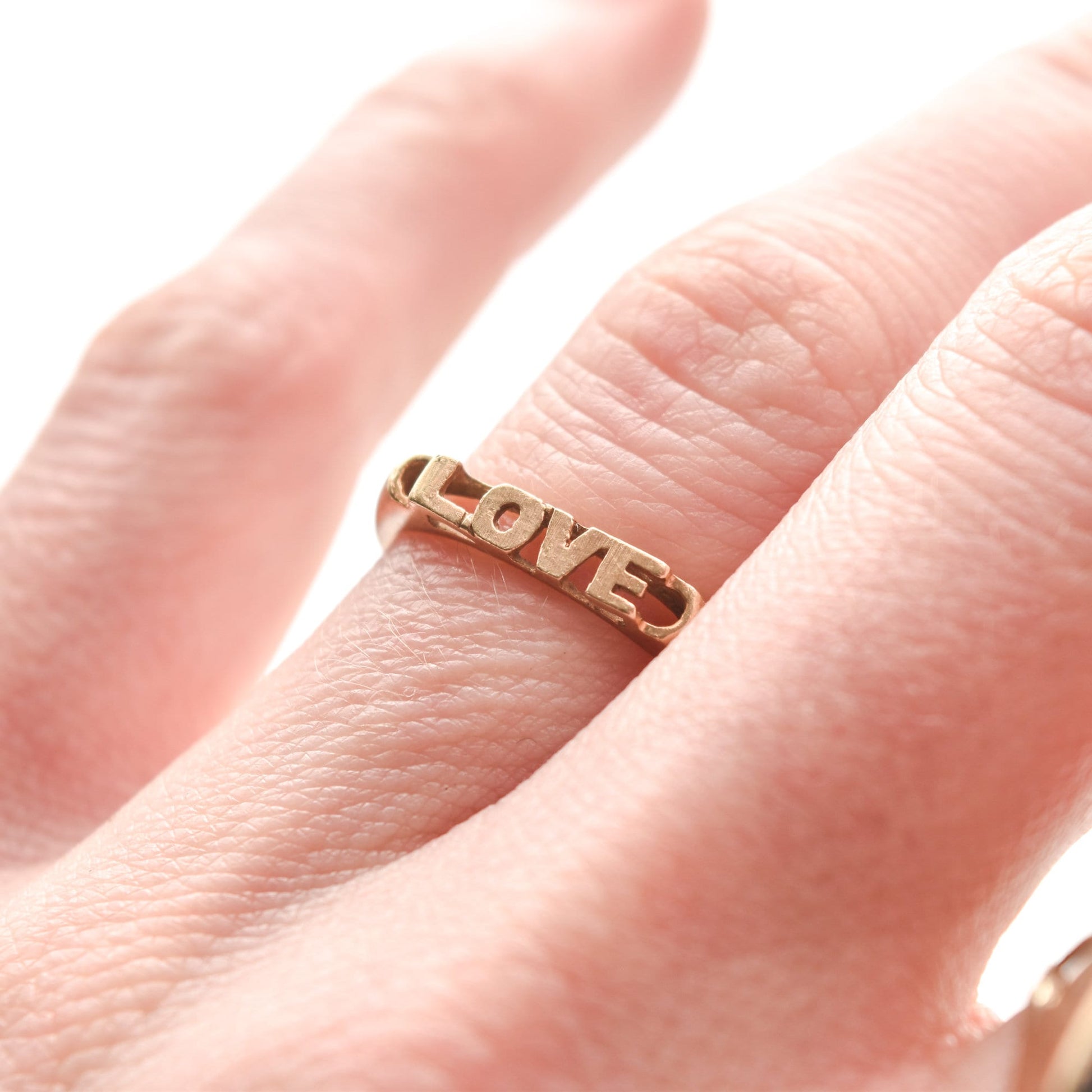 14K yellow gold minimalist 'LOVE' ring on finger, cute stacking ring, Valentine's Day gift idea, size 6.75 US.