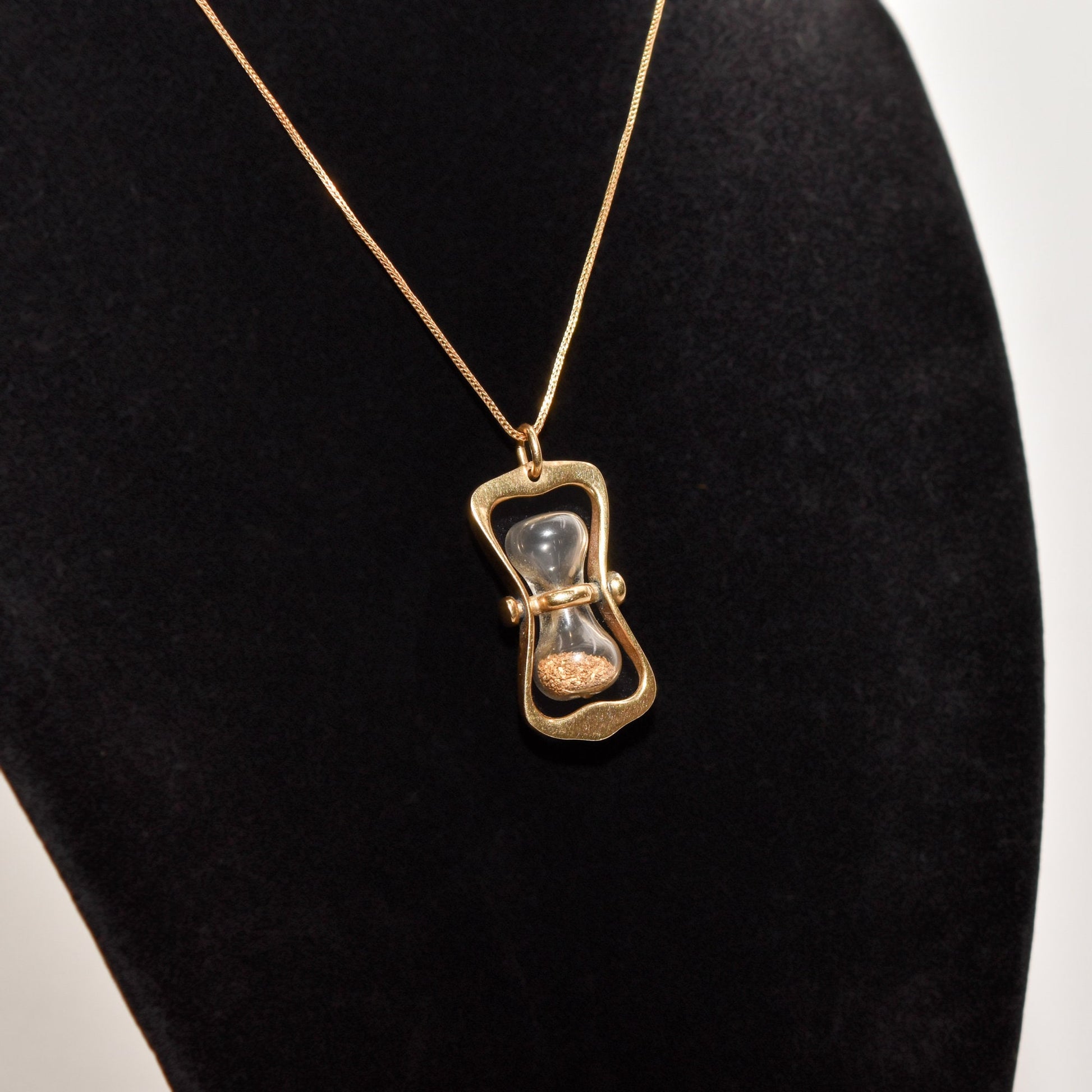 14K gold hourglass pendant with gold dust on a chain, displayed on black mannequin, 36mm movable swivel estate jewelry.