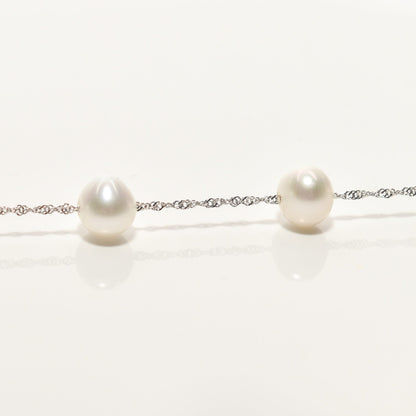 White pearl choker necklace in 14k white gold with pearl station design on a reflective surface, measuring 17.75 inches in length
