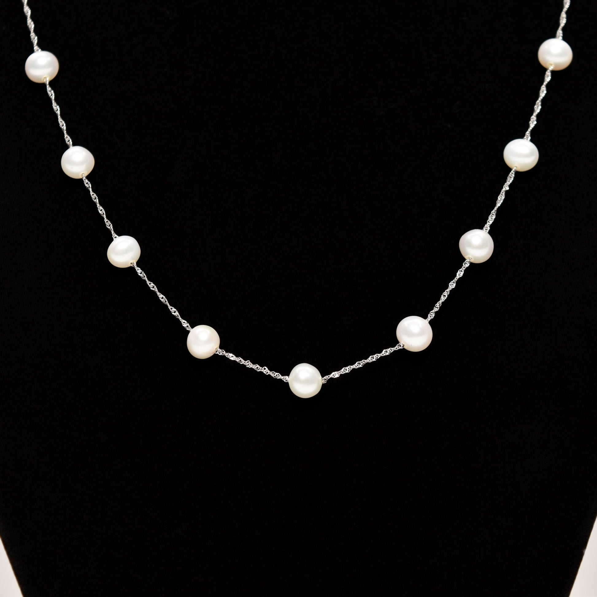 Elegant white pearl choker necklace in 14K white gold with pearl stations on a black display, 17.75 inches long.